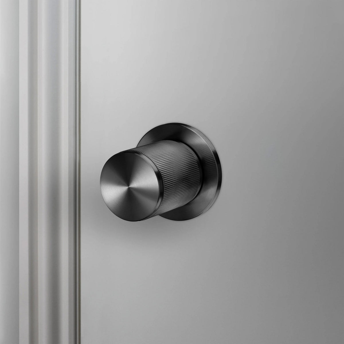 A sleek, dark door stopper protrudes from a light grey wall.