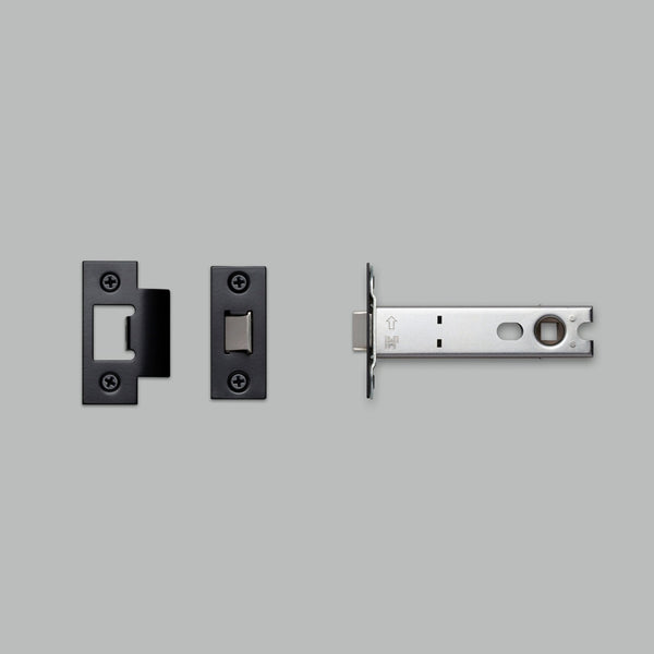 Components of a tubular latch, including the latch mechanism and two black strike plates.