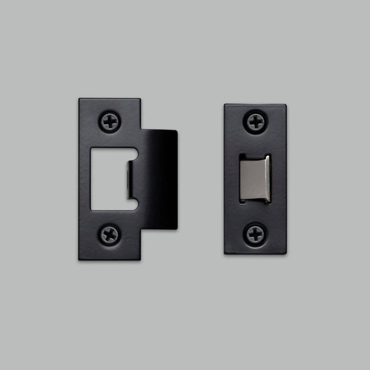 Two black strike plates for a tubular door latch on a grey background.