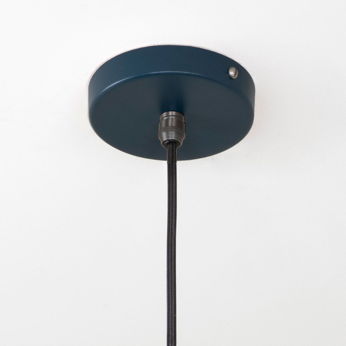 Close-up of the dark blue ceiling rose and black cable for the pendant light.
