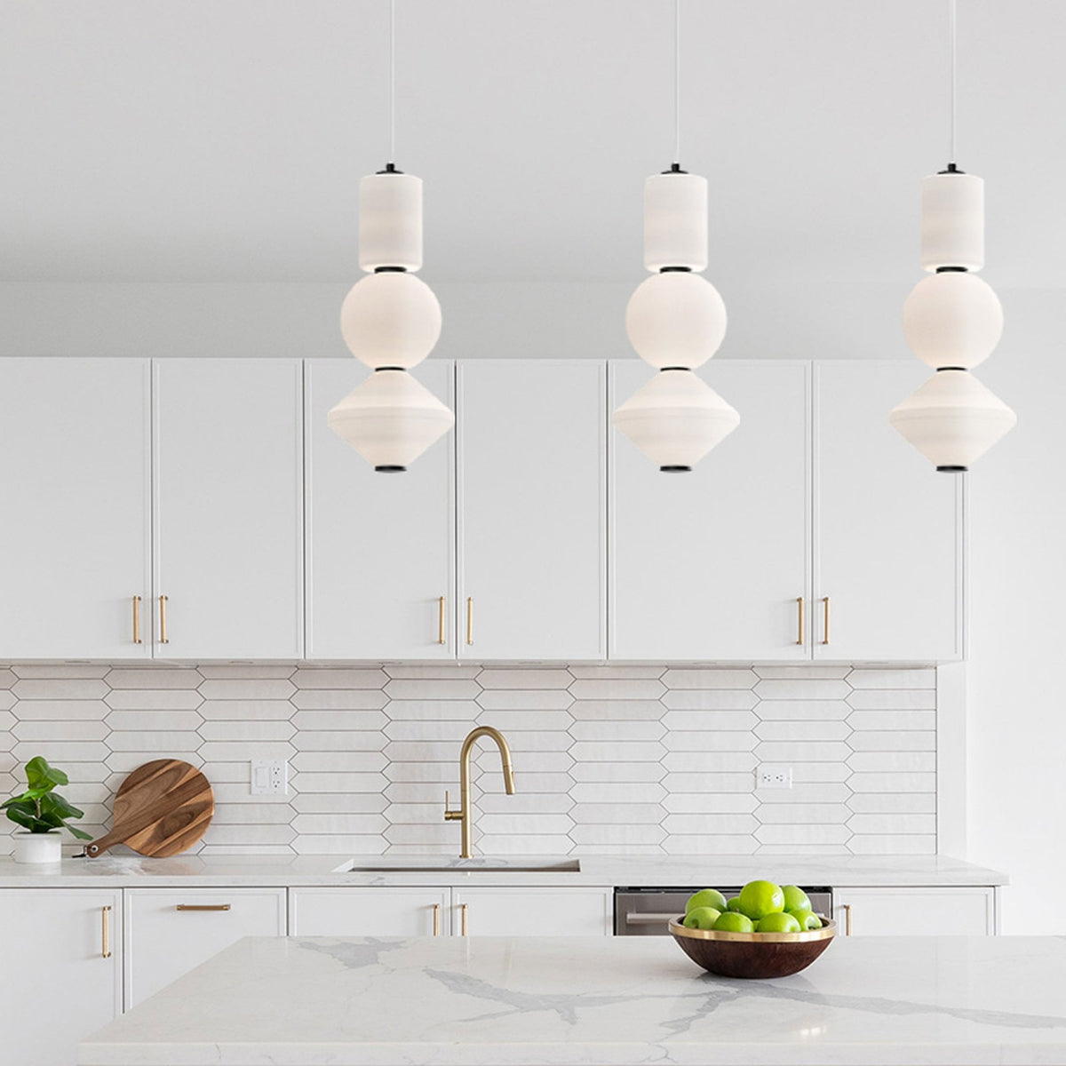 Three pendant lights hang above a kitchen island, illuminating the modern white kitchen.