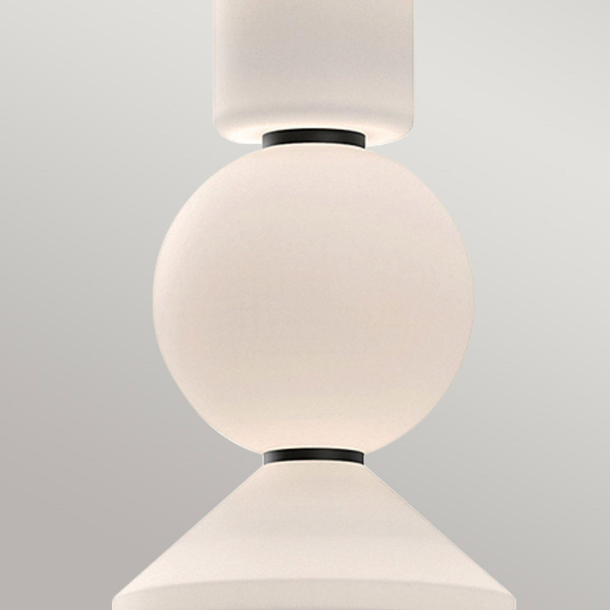 Close-up of the pendant light's cylindrical, spherical, and conical white glass shades.