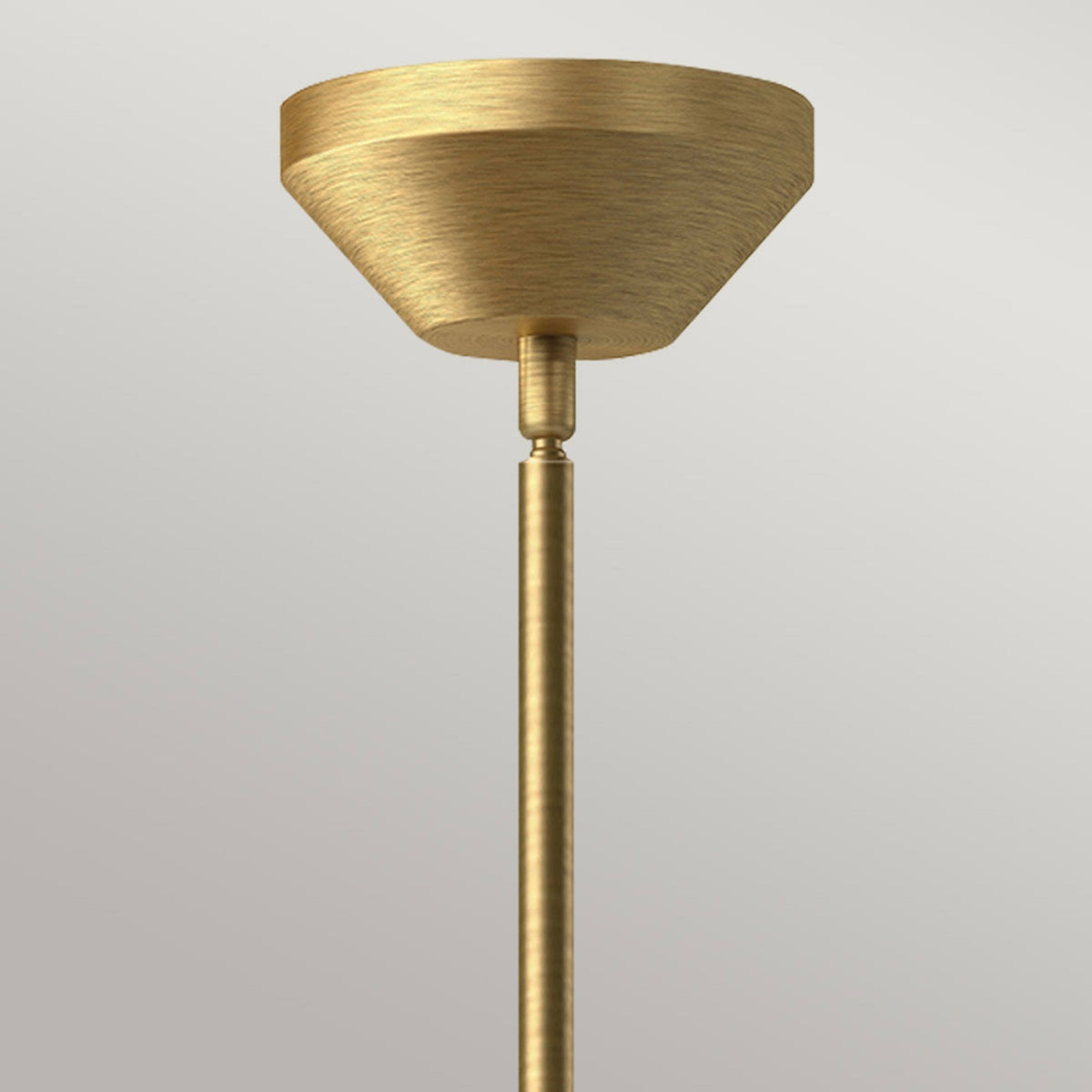 Close-up of the brass ceiling rose and rod of a pendant light.