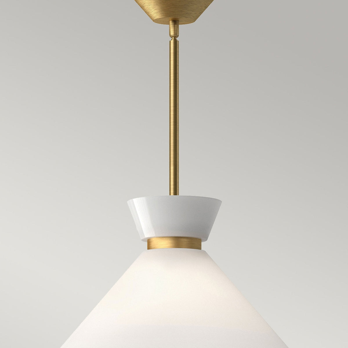 Close-up of a pendant light with a white cone shade and brass detail.