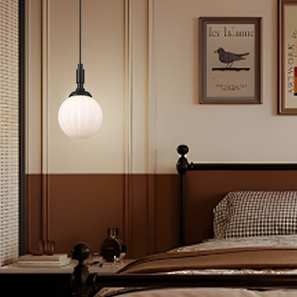 A black pendant light with a white fluted globe shade illuminates a modern bedroom.