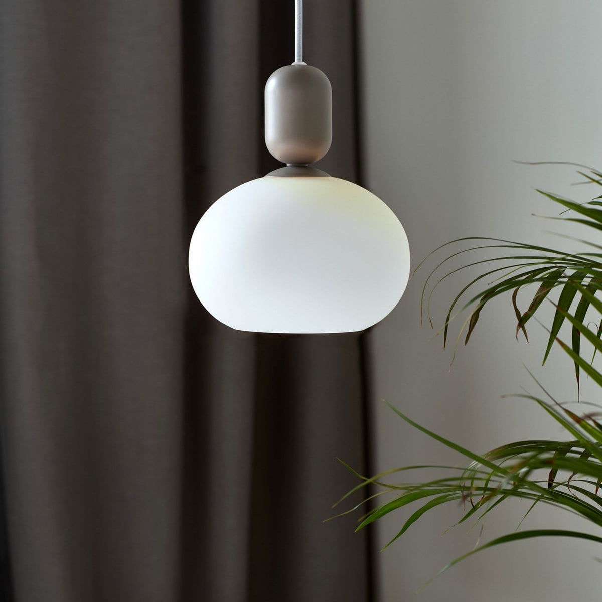 Nordlux Notti 20 Pendant in Grey with Opal Glass Shade, hanging against a dark curtain