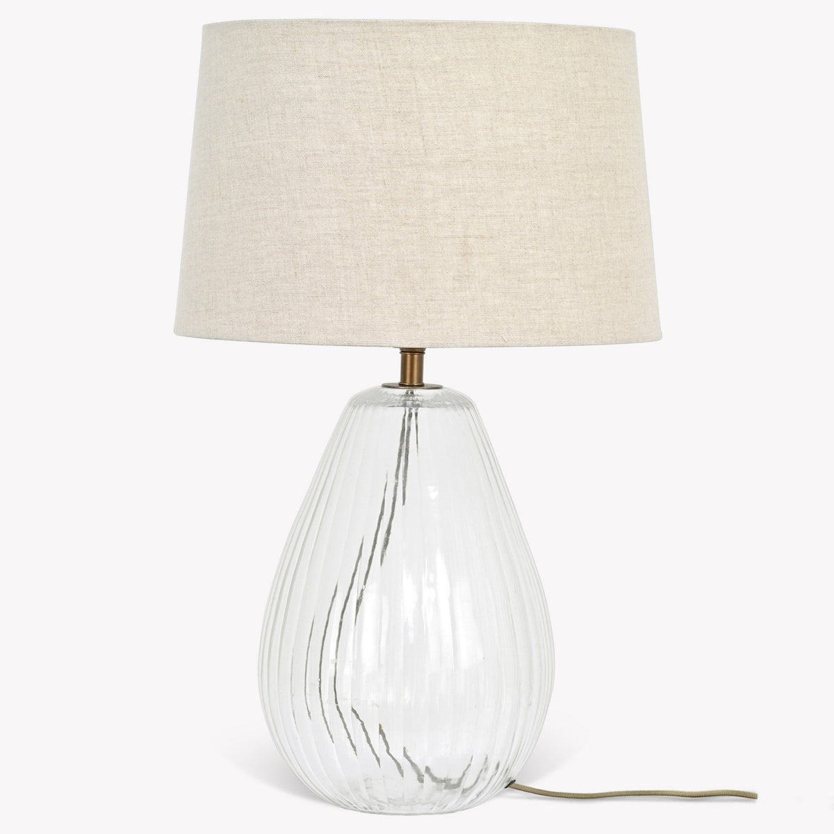 Clear glass table lamp with vertical ridges and a natural linen shade. It has a bronze neck and a brown cord.