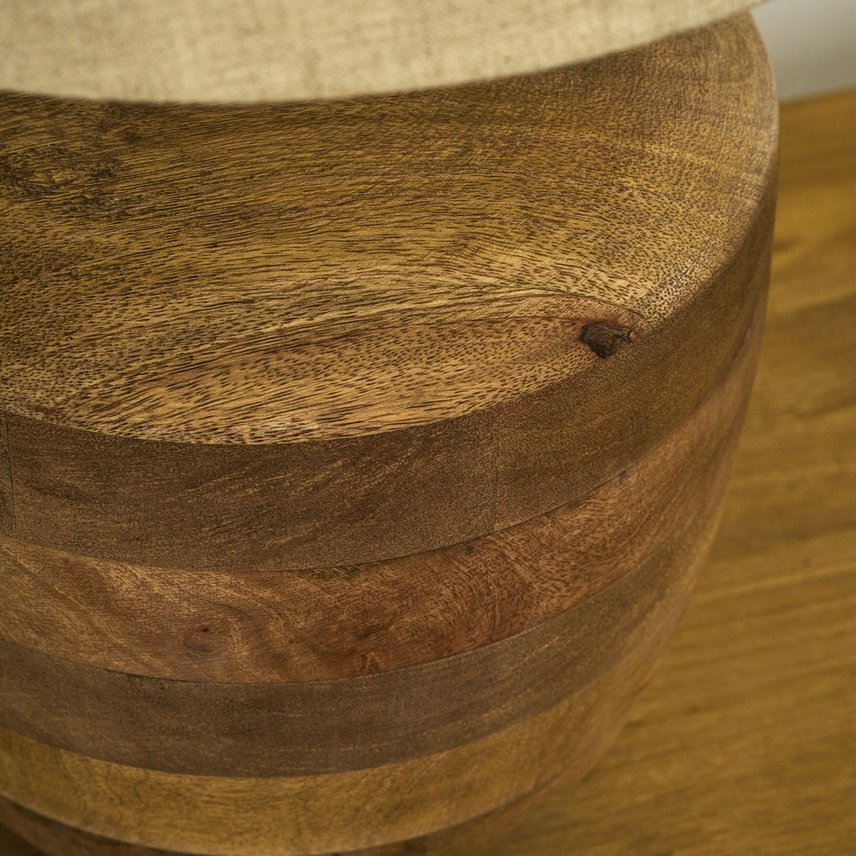 Close-up of a wooden lamp base with a light fabric shade, showing natural wood grain and a small knot.