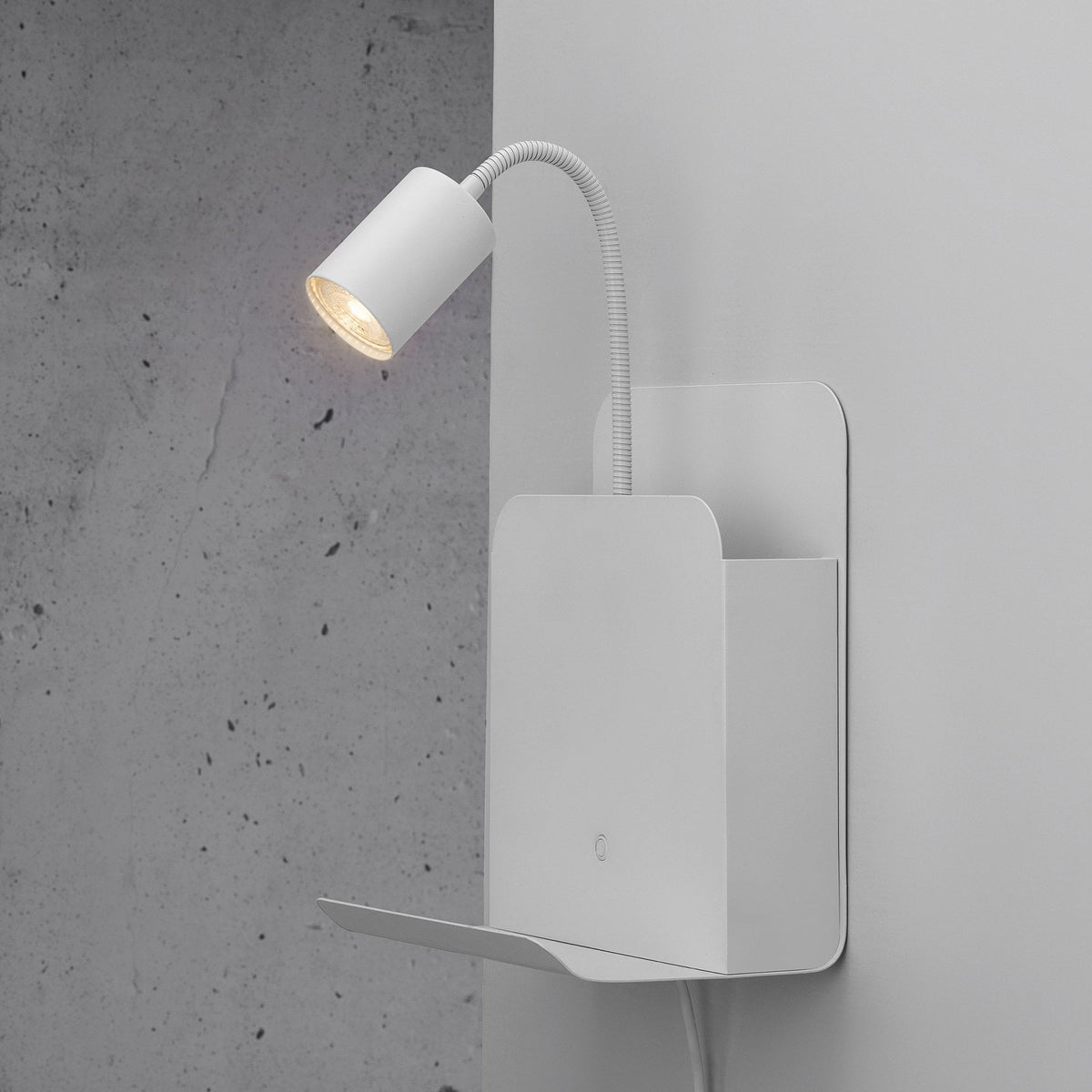 White wall shelf with an attached lamp, mounted on a textured grey wall.
