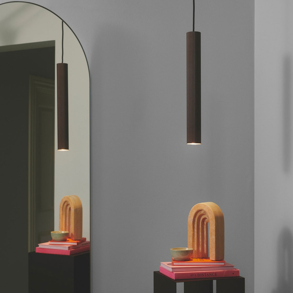 Two cylindrical brown pendant lights hanging in a modern hallway space.