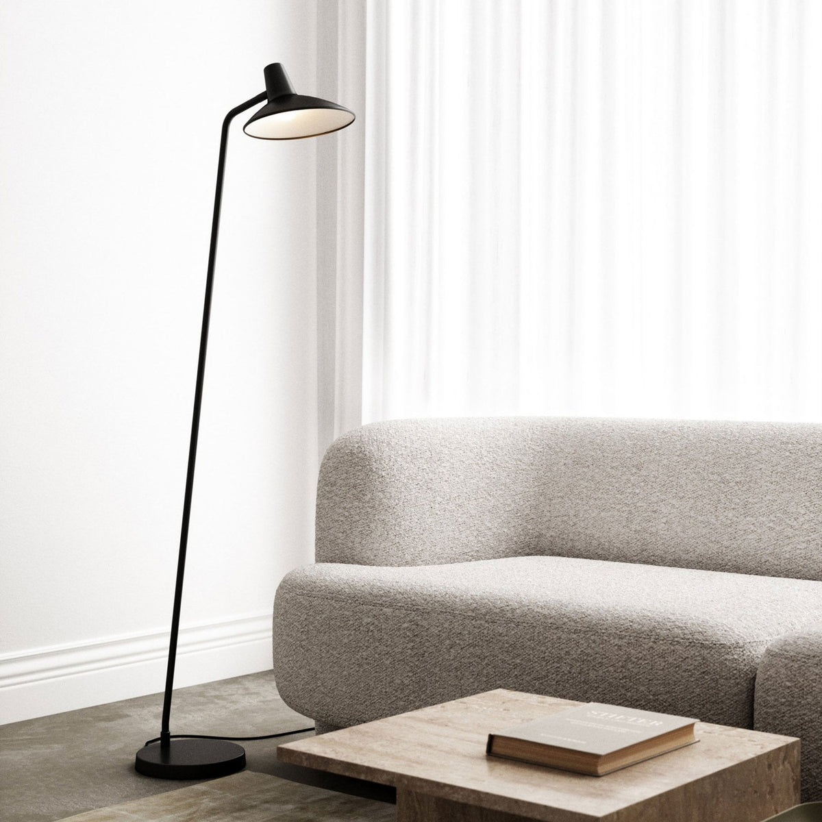DFTP By Nordlux Darci Adjustable Floor Lamp in Black next to a light grey sofa and a coffee table