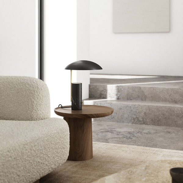 Table lamp with black marble base and matte black shade on a wooden side table.