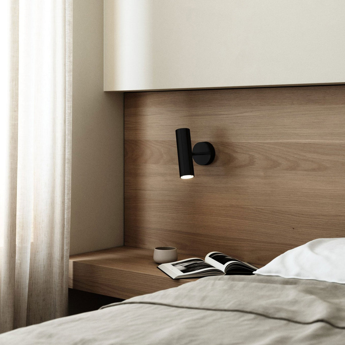 DFTP By Nordlux Mib Plugged Adjustable Wall Spotlight in Black mounted on a wooden headboard