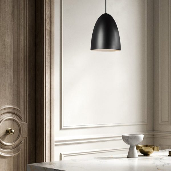 A black pendant light hanging above a white marble counter in a chic, minimalist room.