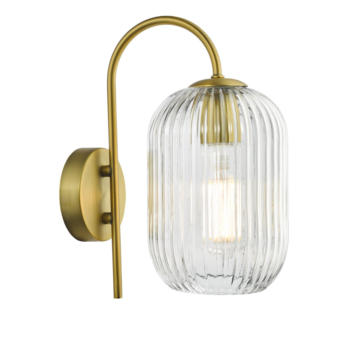 A brass wall sconce with a curved arm and a ribbed glass shade, illuminating a warm glow.
