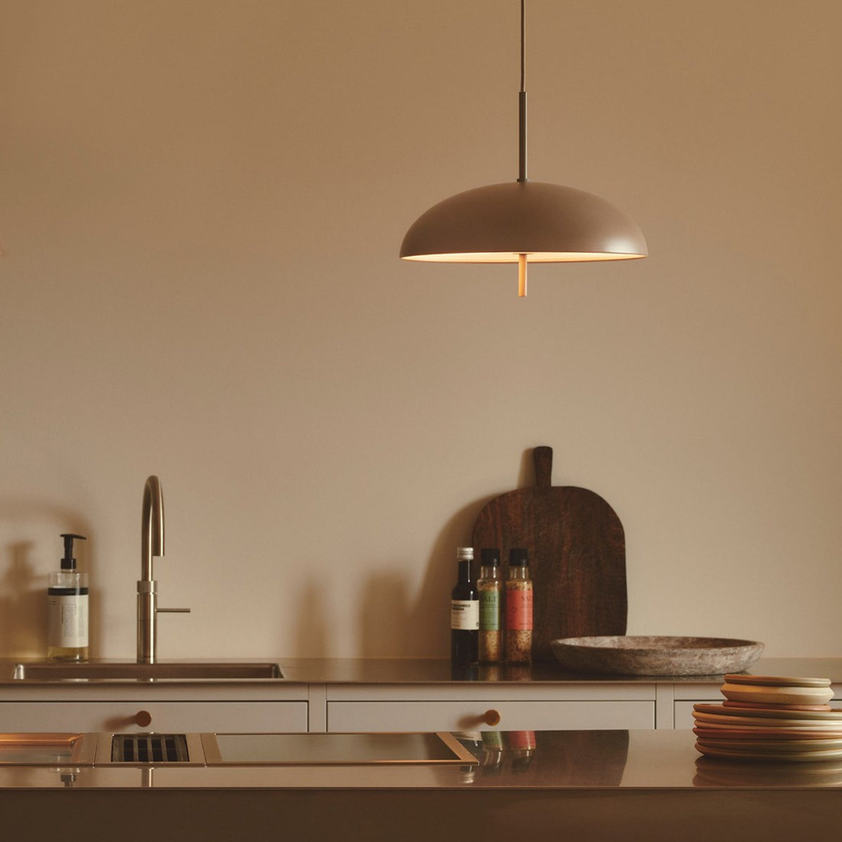 A kitchen island with a sink, a faucet, a soap dispenser, and a stack of plates
