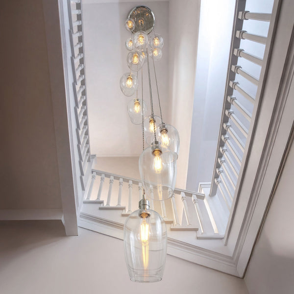 A multi-bulb pendant light fixture with glass shades, seen from above, hanging in a stairwell.