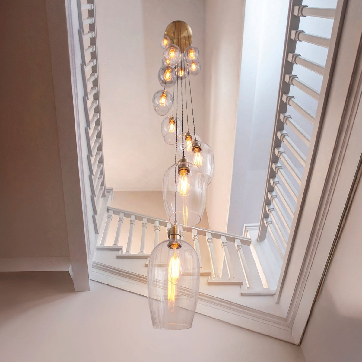 Looking down at a spiral chandelier with many glass pendants, illuminating a stairwell.