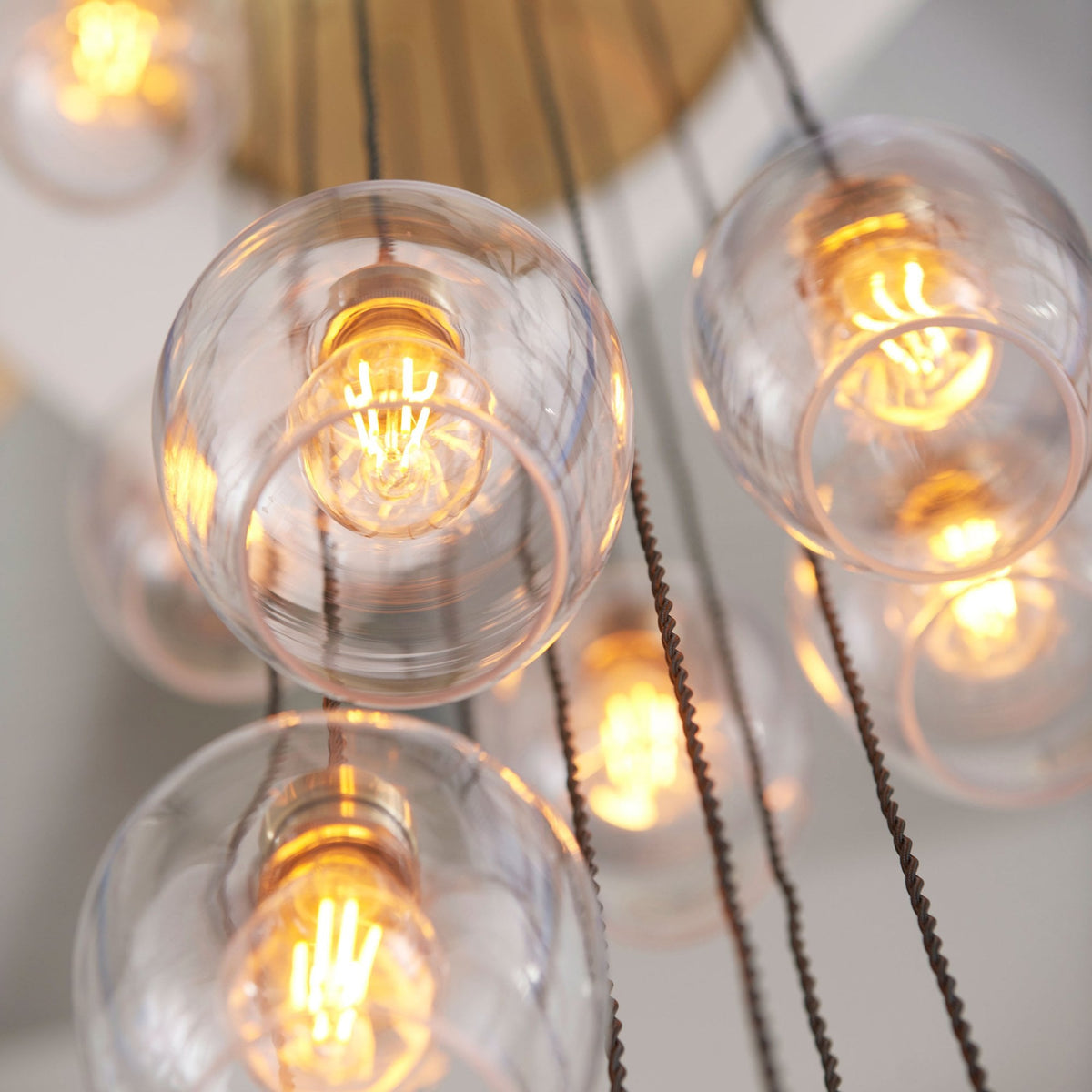 A close-up of clear glass pendant lights with warm, visible filaments.