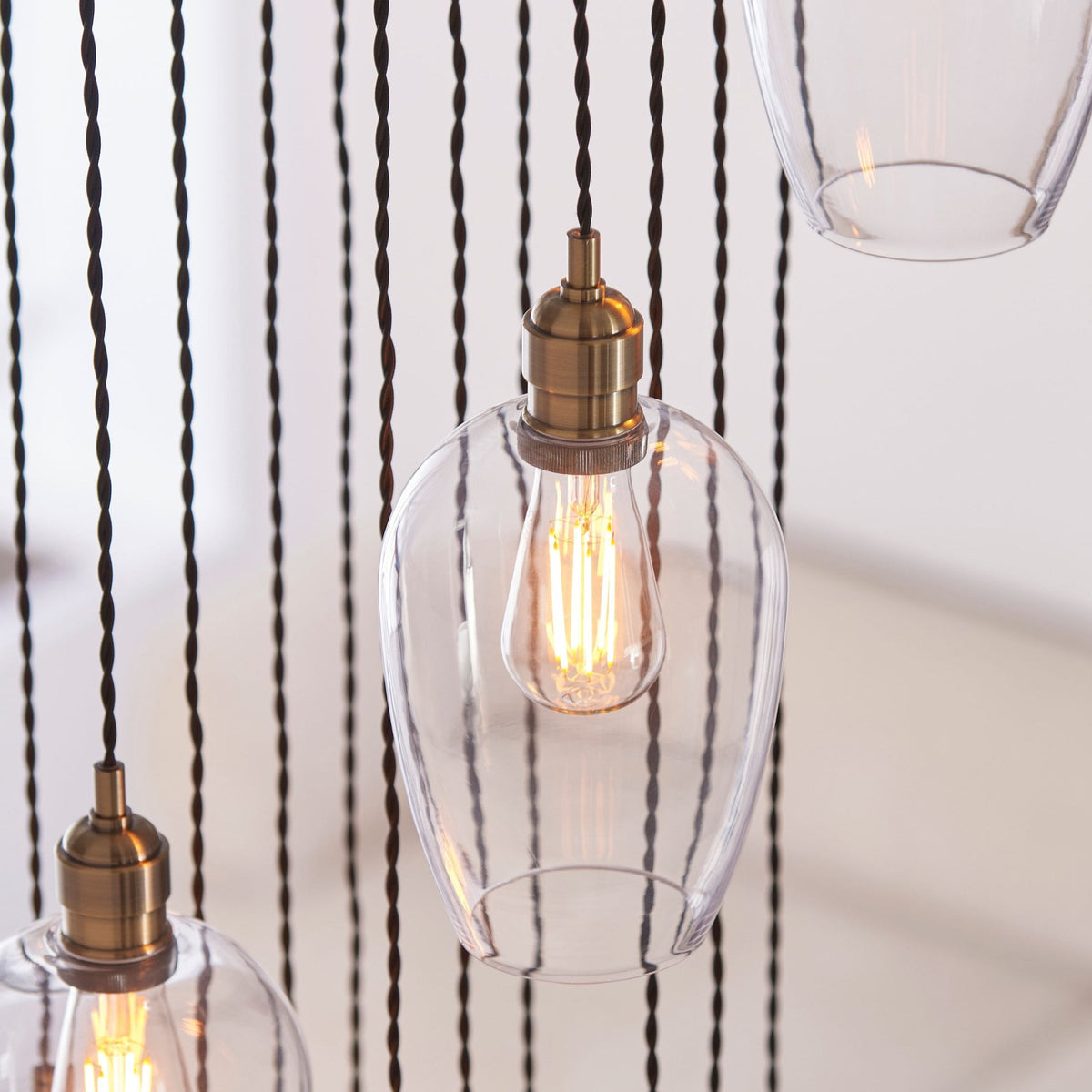 A close-up of a single glass pendant light with a brass fixture and a visible filament bulb.
