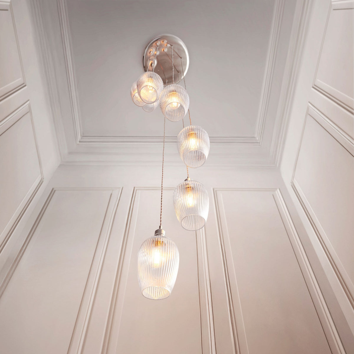 A stylish four-light pendant with clear glass shades illuminates a well-appointed room, highlighting its elegant design.