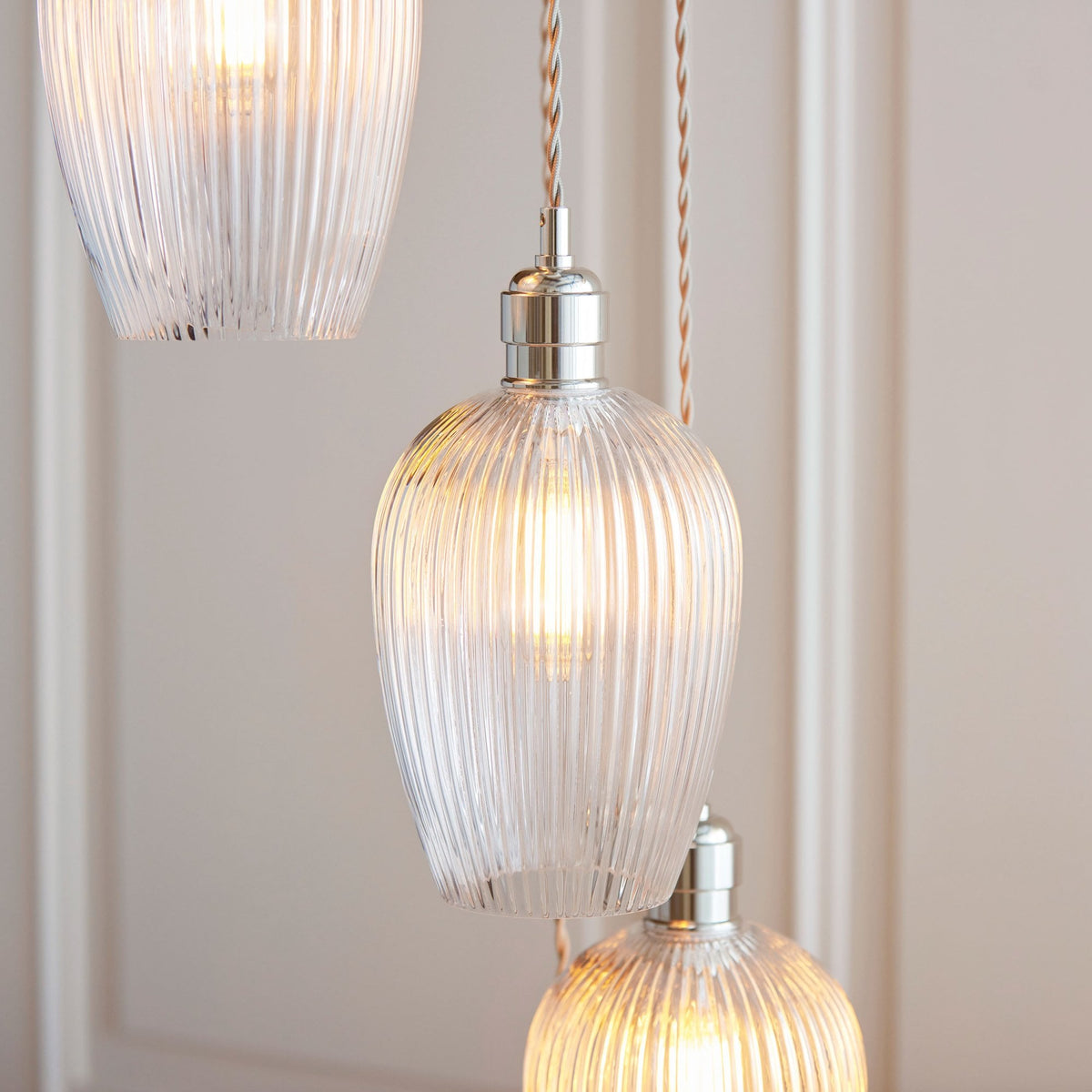 Close-up of ribbed clear glass pendant lights, showcasing the texture and warm light, enhancing the fixture's appeal.