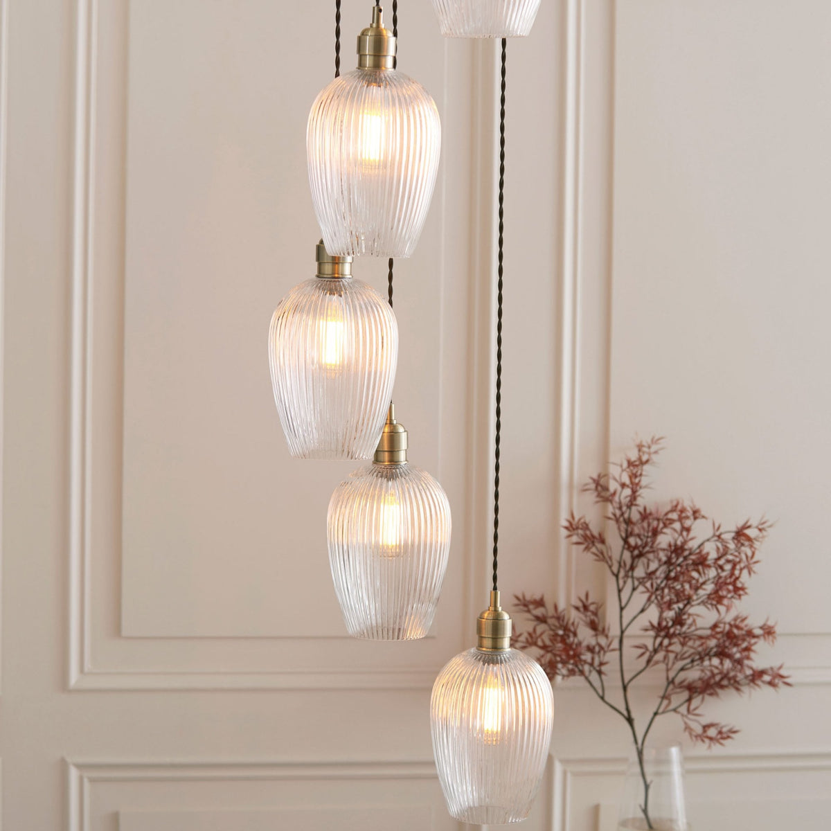 A close-up of four of the seven textured glass pendant lights, illuminated against a white paneled wall.
