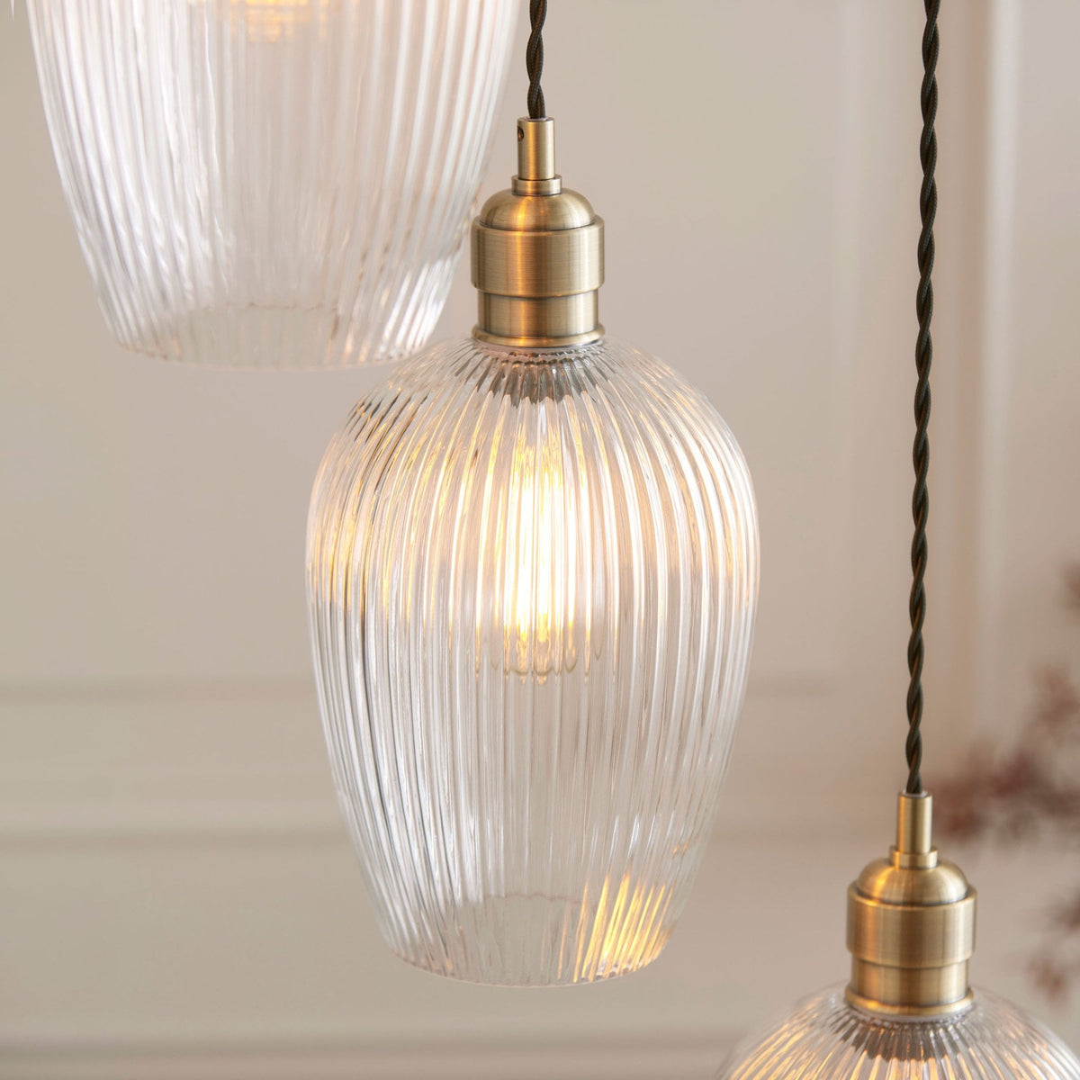 A detailed close-up of one of the ribbed glass pendant shades with a brass fitting and an exposed bulb.