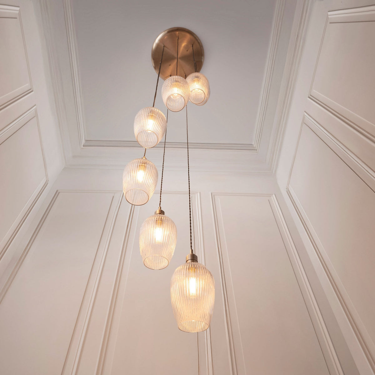 A multi-pendant cluster light featuring seven irregular-shaped glass shades, hanging elegantly in a room.