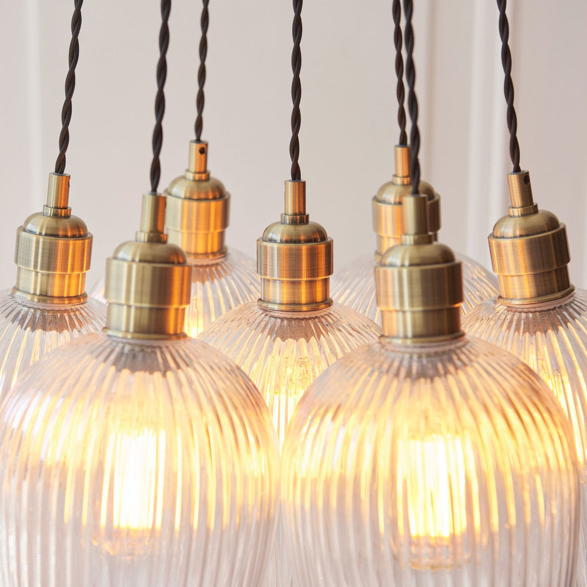 A detailed close-up of the Volia Glass Chandelier, showing the ribbed glass shades and antique brass hardware.