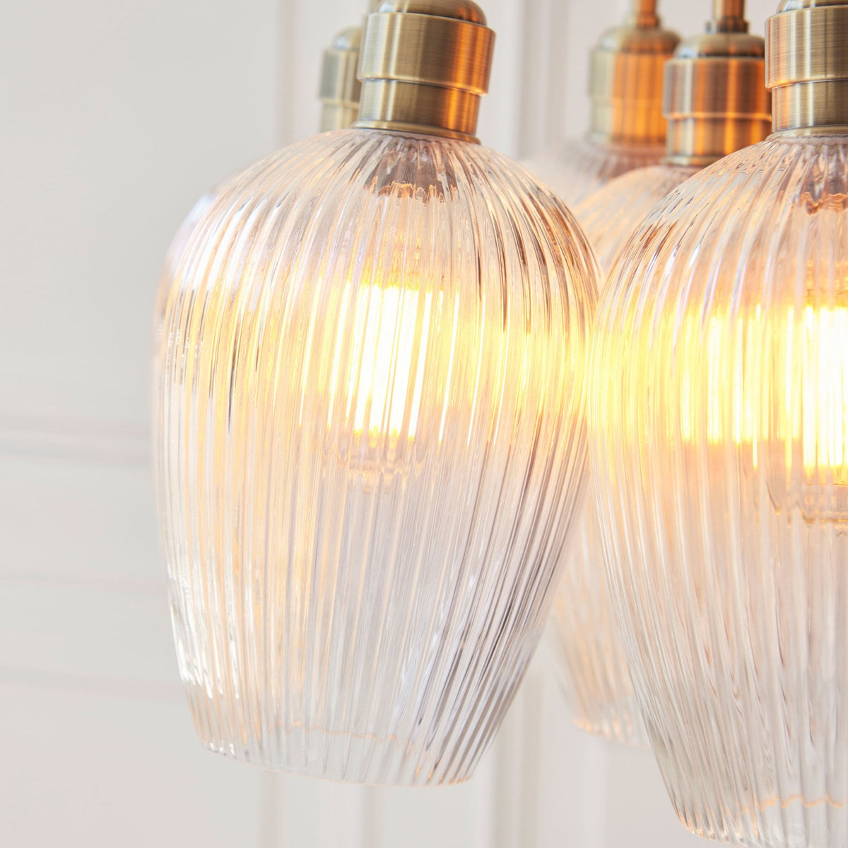 A detailed close-up of the Volia Glass Chandelier, highlighting the textured ribbed glass and warm light from the bulbs.