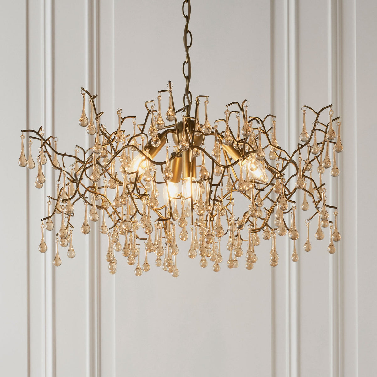 A close-up view of the 12-light bronze chandelier, highlighting its intricate glass droplets and metal branches.