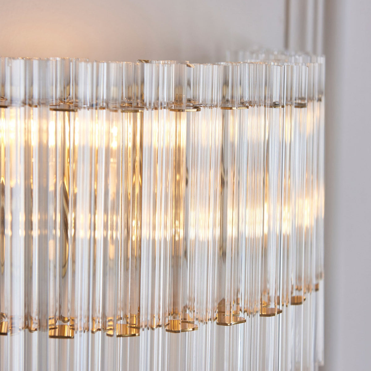 A detailed close-up of the elegant fluted glass rods of a wall sconce, highlighting the warm light within.