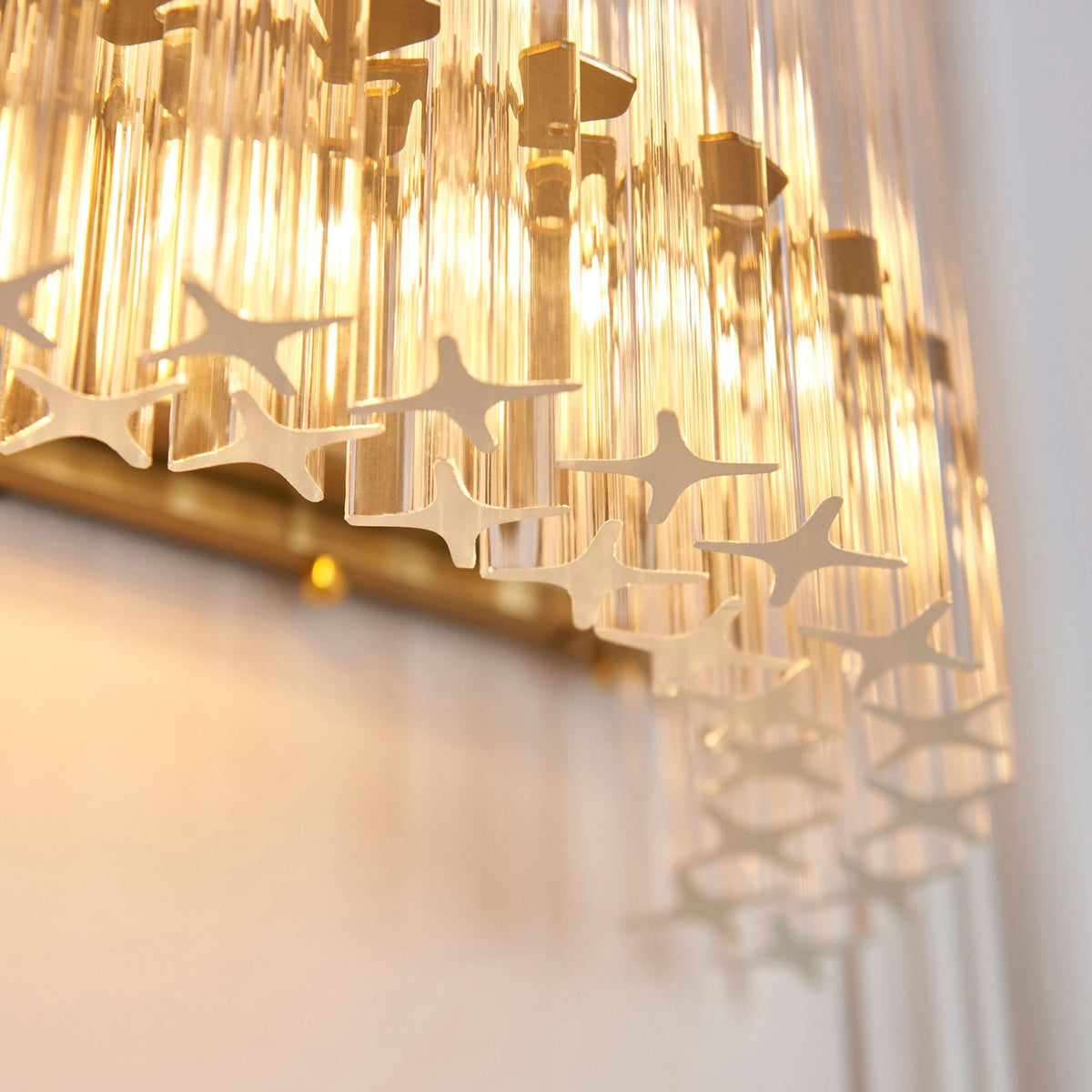 A close-up view showing the intricate star-shaped detailing on the bottom edge of a curved fluted glass wall sconce.