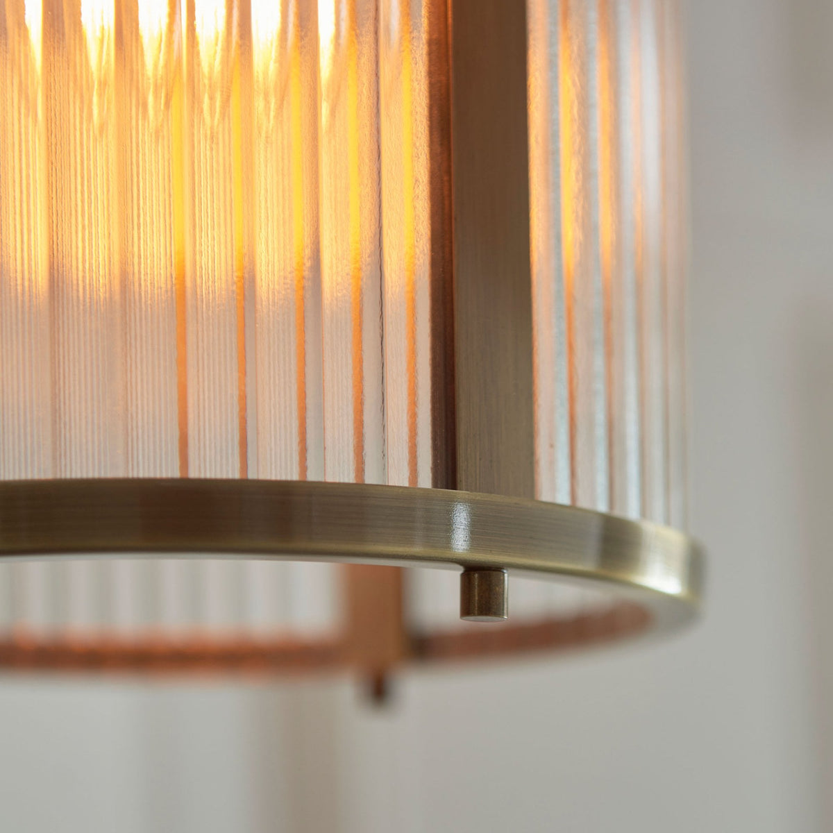 Un gros plan d'un pendentif lanterne cannelé en verre et laiton avec une finition patinée brossée.