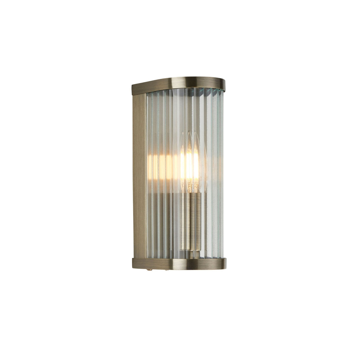 A minimalist, gold-plated, wall-mounted light with a fluted glass shade, casting a soft glow.