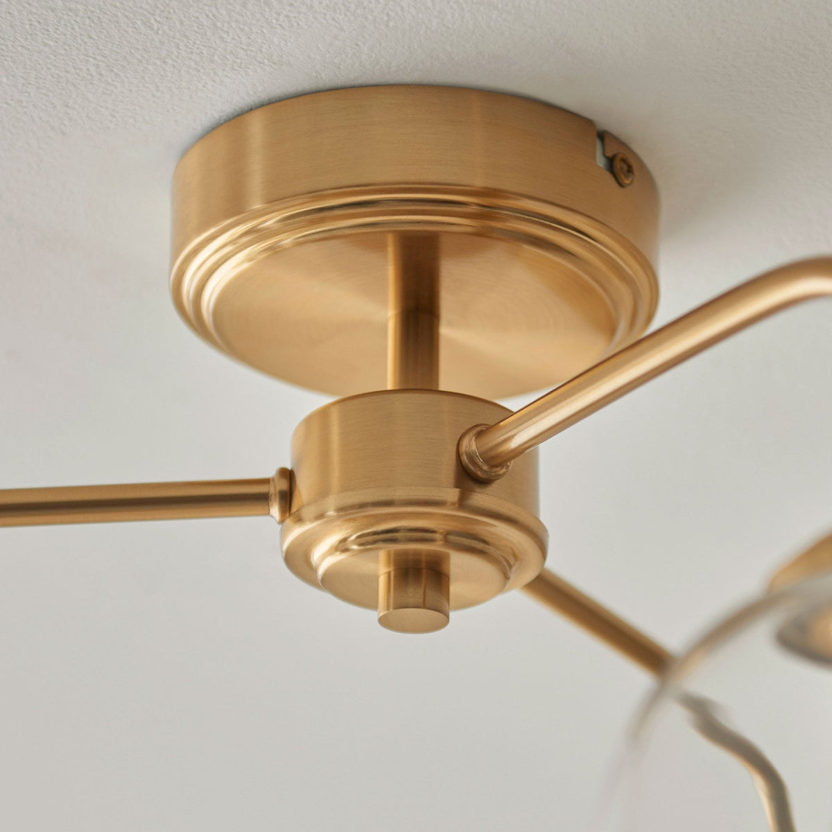 A detailed view of the brass ceiling rose and arms of a three-light fixture.