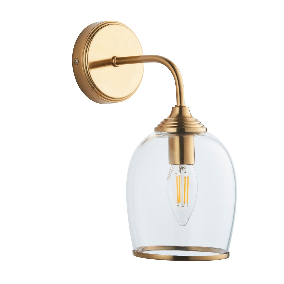 A brass wall light with a clear glass shade, featuring a visible filament bulb, isolated on a white background.