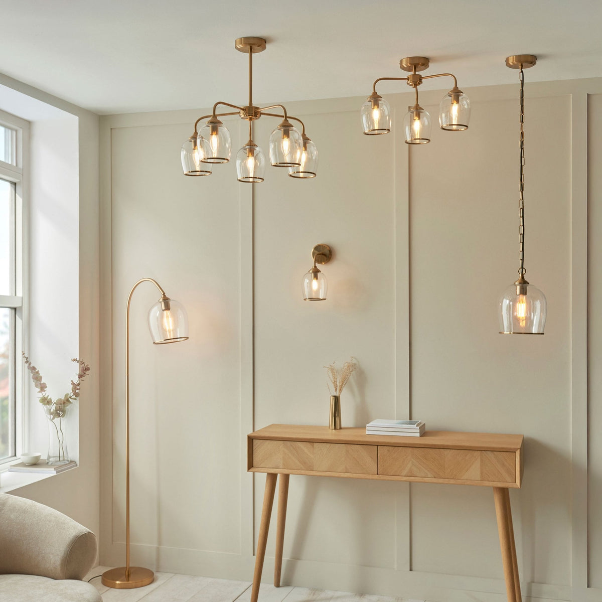 A room featuring multiple brass and glass lighting fixtures, including chandeliers, a floor lamp, and a wall light.