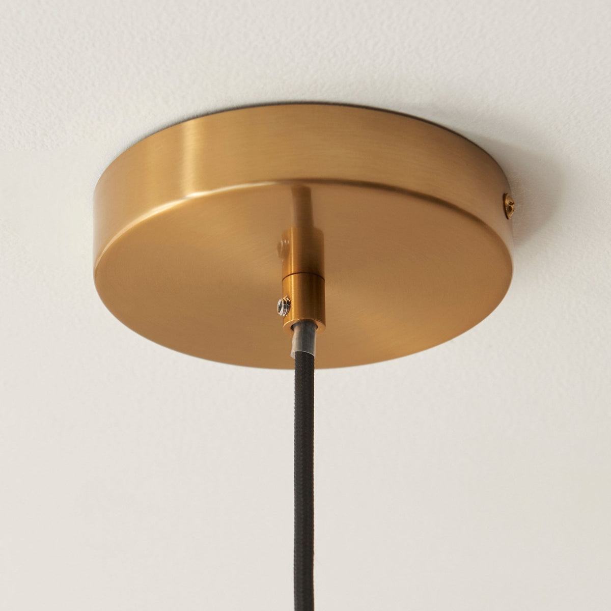 Close-up of a polished gold ceiling rose, providing a secure and decorative mount for a pendant light.