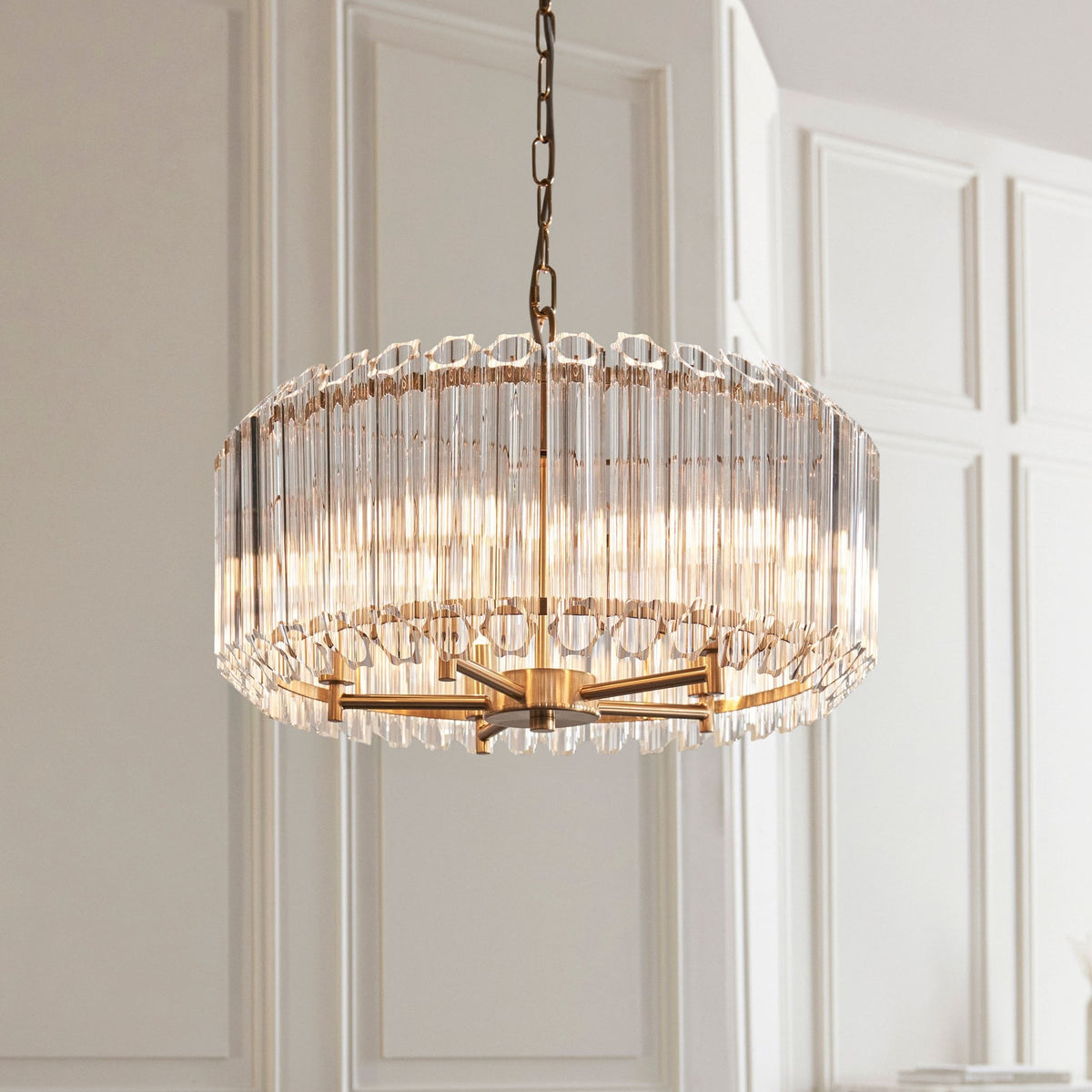 A close-up of a golden chandelier with glass rods, highlighting its intricate design and warm glow.