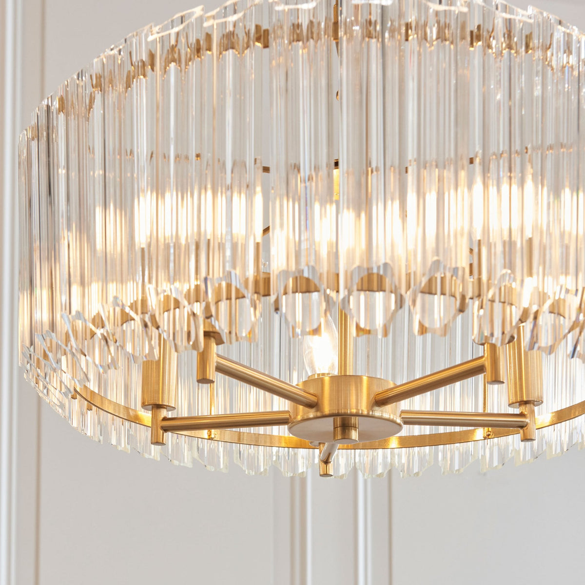 An extreme close-up of the golden chandelier, showing the detailed glass rods and metallic frame.
