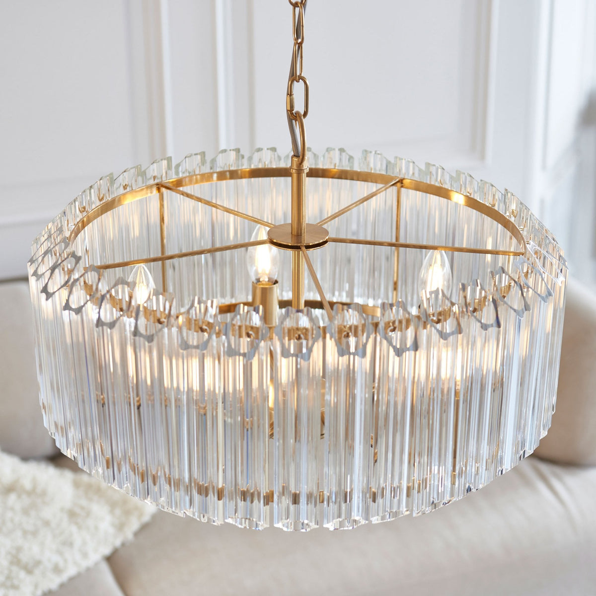 A close-up of a golden chandelier with clear glass rods, showcasing its elegant design.