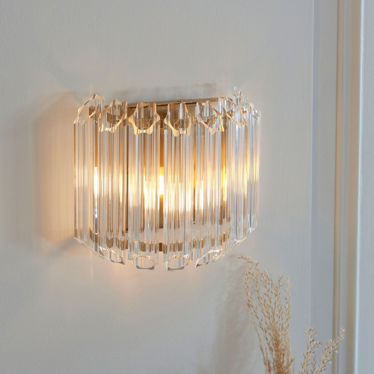 A luxurious wall sconce with vertical crystal rods and a warm glow, adding elegance to a contemporary interior.