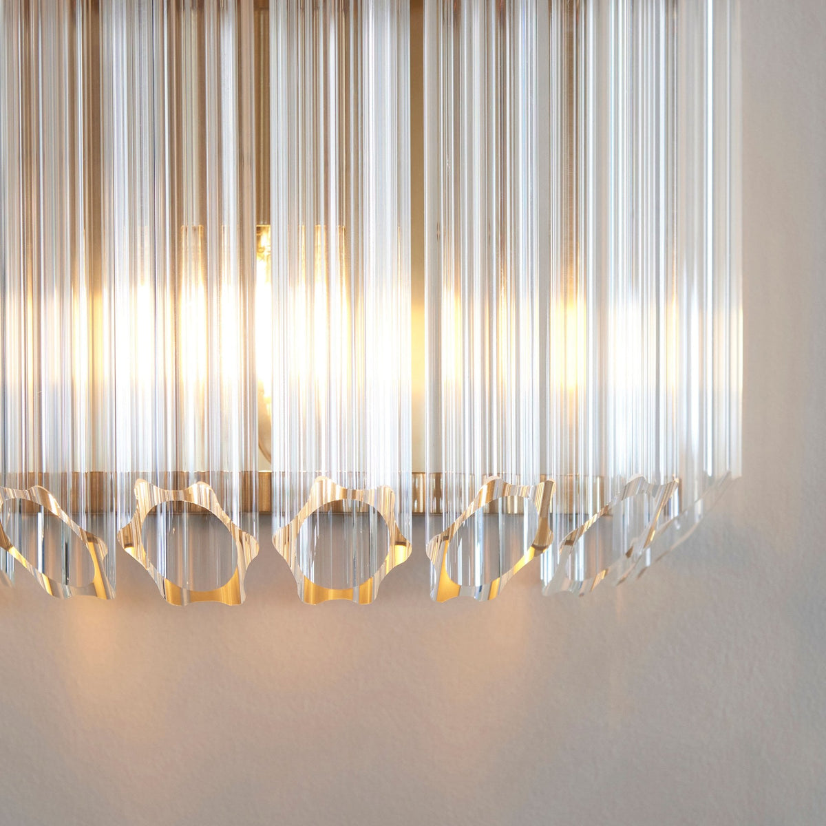 A detailed view of the bottom portion of a crystal wall light, showing the decorative cutouts and radiant light.