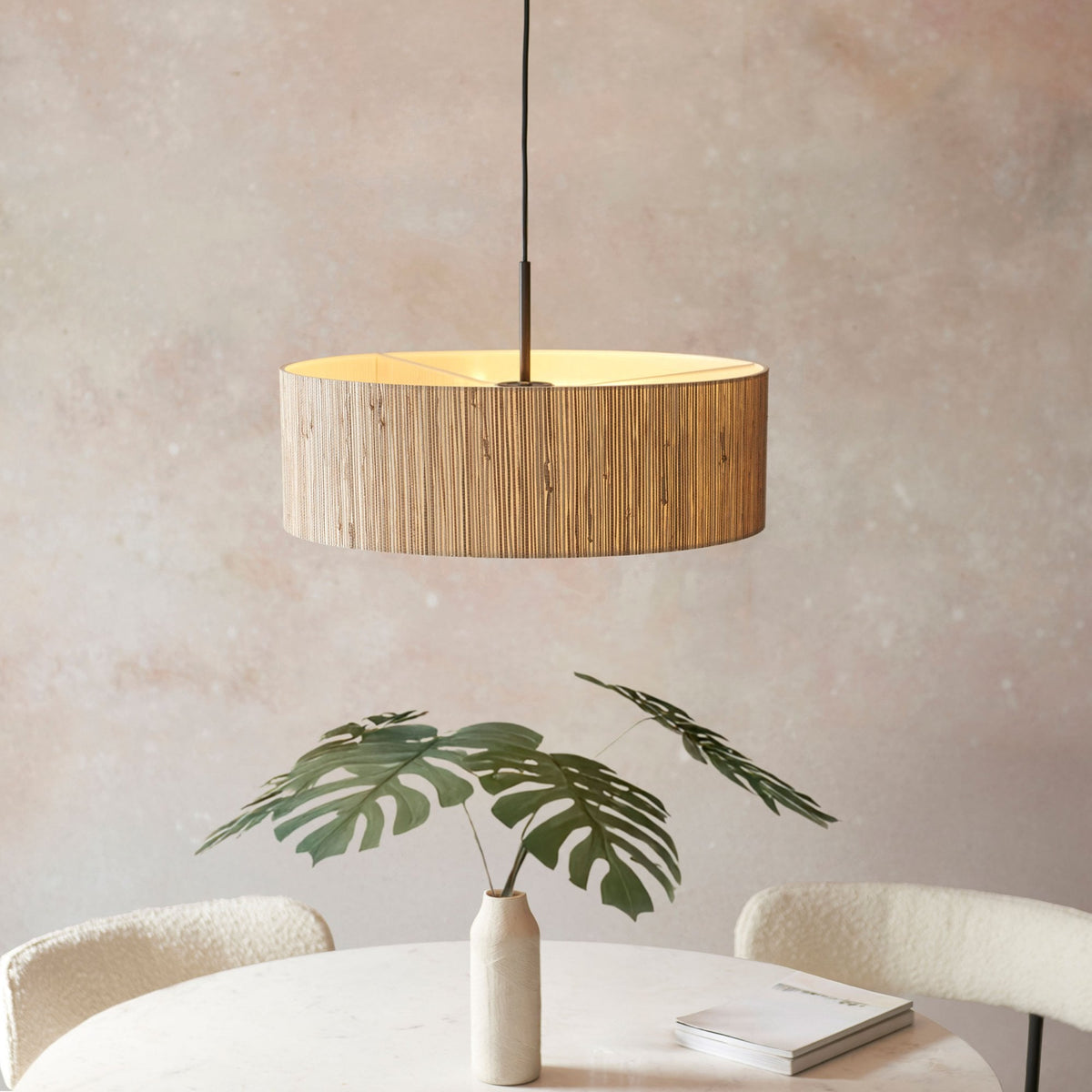 A view of the pendant light with its warm glow illuminating a dining table setting with a decorative plant.