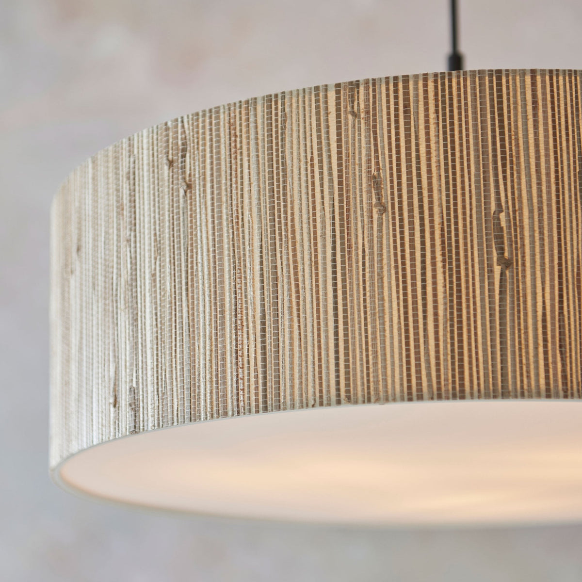 An extreme close-up of the natural wood slats on the drum-shaped pendant light's shade.