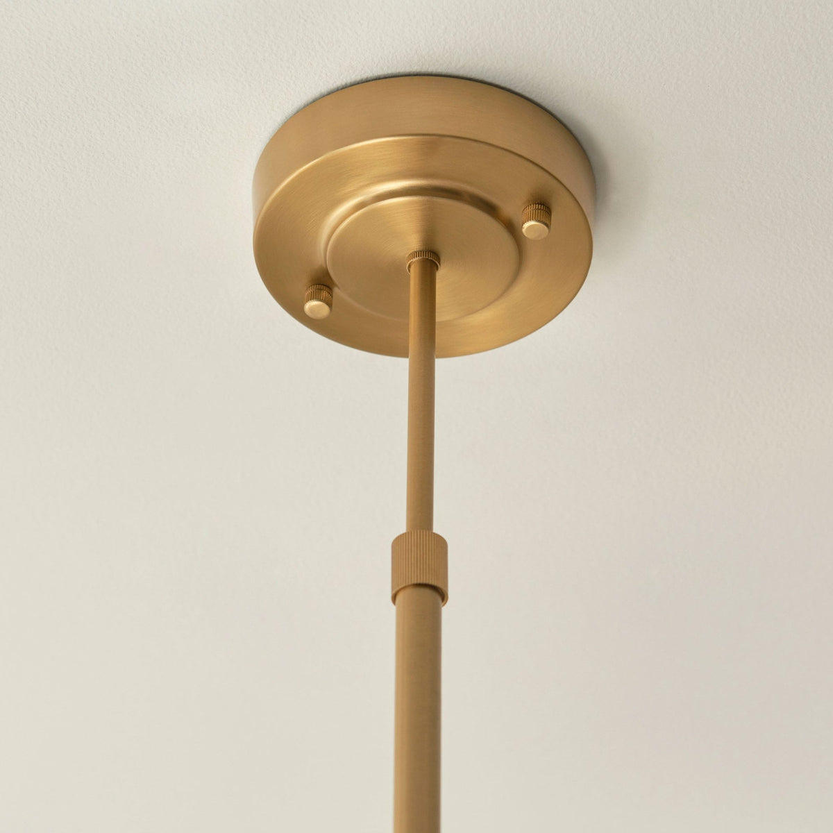 Un primer plano del dosel de techo redondo dorado y el vástago del candelabro.