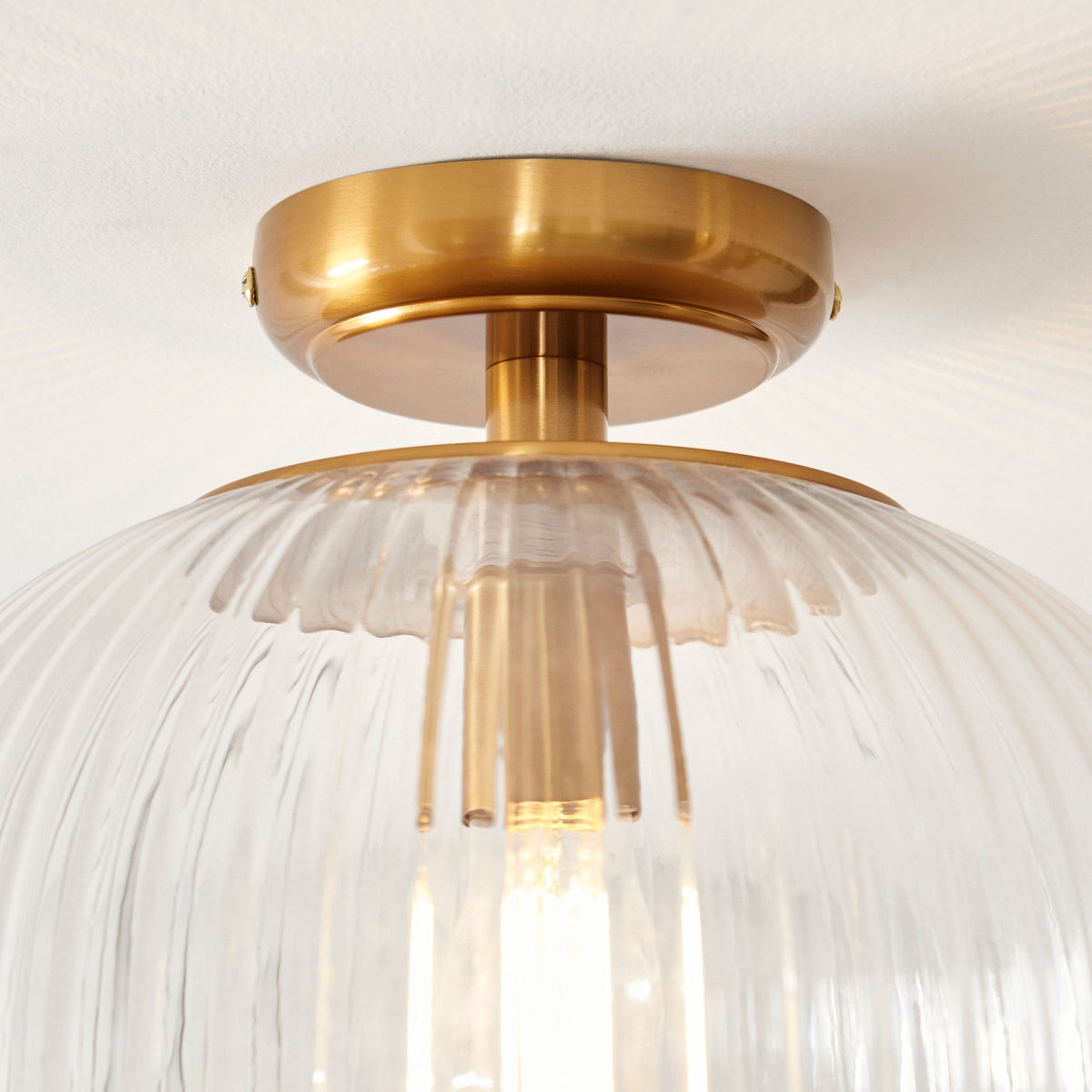 A detailed close-up of the brass base and ribbed glass texture of the ceiling light.