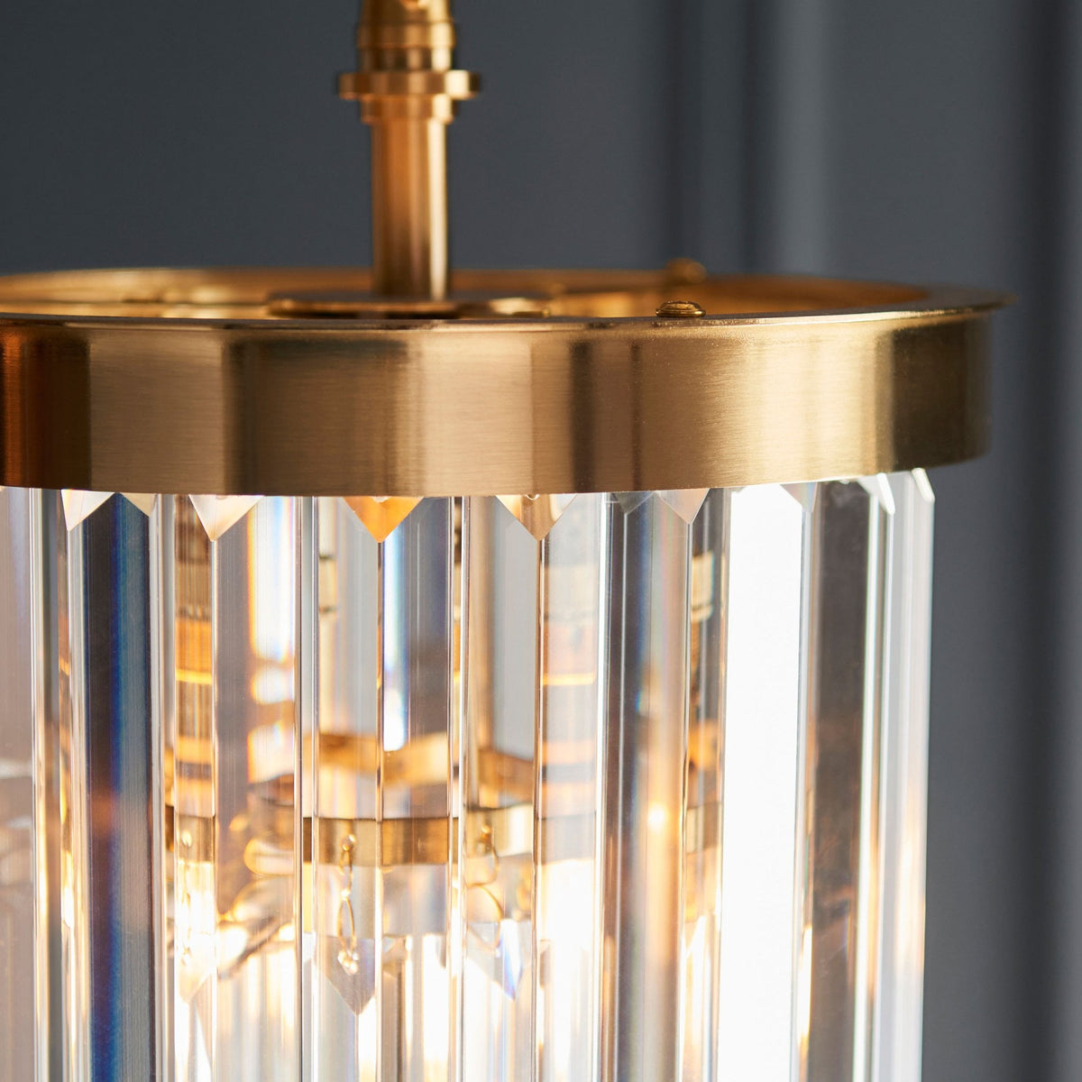 A close-up of a pendant light revealing its brass cap and the intricate arrangement of tiered clear glass rods.